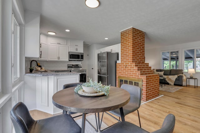 2870 Hamilton Ave, Columbus, OH 43224 - dining space with light wood-style flooring, a brick fireplace, and recessed lighting