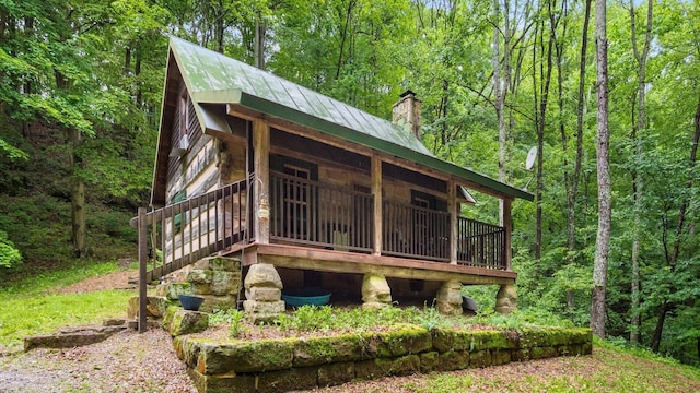 24000 State Route 180, Rockbridge, OH 43149 - view of front facade featuring a chimney, a wooded view, and a metal roof
