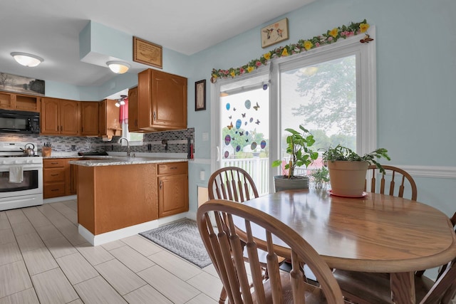 568 Swackhammer Rd, Circleville, OH 43113 - kitchen featuring white stove, black microwave, brown cabinets, decorative backsplash, and light countertops