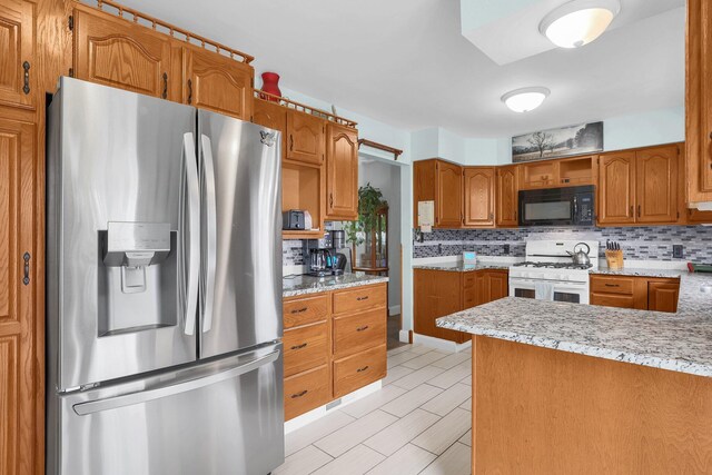 568 Swackhammer Rd, Circleville, OH 43113 - kitchen featuring stainless steel refrigerator with ice dispenser, black microwave, gas range gas stove, decorative backsplash, and brown cabinets