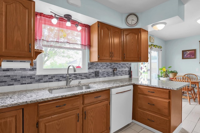 568 Swackhammer Rd, Circleville, OH 43113 - kitchen with white dishwasher, a peninsula, decorative backsplash, brown cabinetry, and light stone counters