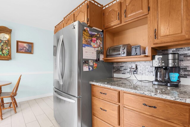 568 Swackhammer Rd, Circleville, OH 43113 - kitchen with freestanding refrigerator, tasteful backsplash, light stone countertops, and brown cabinetry