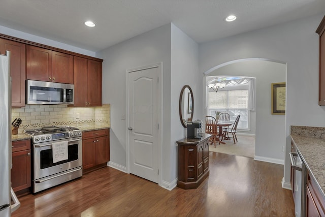5685 Slater Rdg, Hilliard, OH 43026 - kitchen with stainless steel appliances, dark wood-style floors, tasteful backsplash, light stone countertops, and recessed lighting