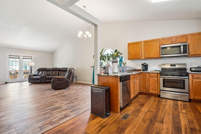 921 Harbinger Cir E, Columbus, OH 43213 - kitchen with stainless steel appliances, vaulted ceiling, brown cabinets, decorative backsplash, and dark wood-style flooring