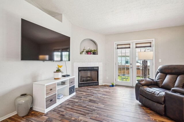 921 Harbinger Cir E, Columbus, OH 43213 - living area featuring dark wood finished floors, a tile fireplace, a textured ceiling, and french doors
