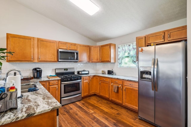 921 Harbinger Cir E, Columbus, OH 43213 - kitchen with stainless steel appliances, lofted ceiling, brown cabinets, backsplash, and dark wood-type flooring