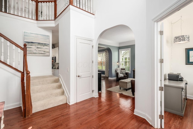 7212 New Albany Links Dr, New Albany, OH 43054 - foyer featuring arched walkways, wood finished floors, stairway, crown molding, and a towering ceiling