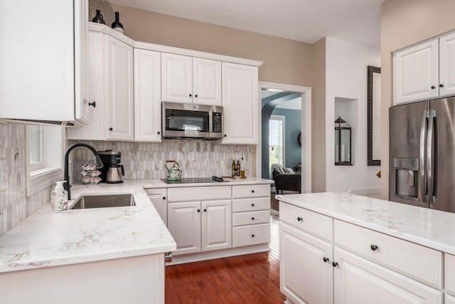 7212 New Albany Links Dr, New Albany, OH 43054 - kitchen featuring stainless steel appliances, tasteful backsplash, arched walkways, white cabinetry, and light stone counters