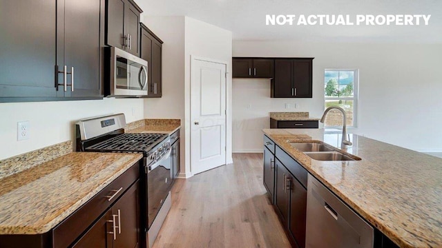 183 Badger Pass, Newark, OH 43055 - kitchen with appliances with stainless steel finishes, light wood-style flooring, light stone counters, and dark brown cabinets