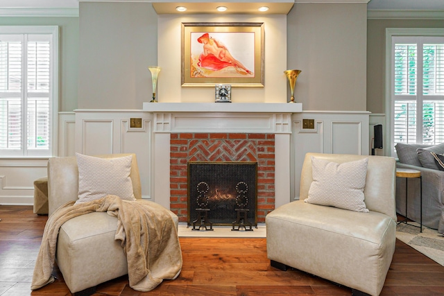 33 E Frankfort St, Columbus, OH 43206 - living area with a decorative wall, a brick fireplace, wainscoting, crown molding, and wood finished floors