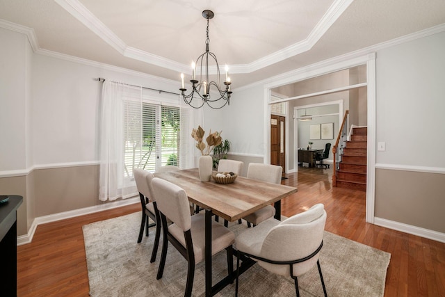 8918 Filiz Ln, Powell, OH 43065 - dining space with a chandelier, a raised ceiling, ornamental molding, wood finished floors, and stairway
