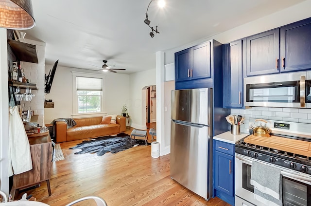 573 E Mithoff St, Columbus, OH 43206 - kitchen with stainless steel appliances, a ceiling fan, blue cabinetry, light wood finished floors, and decorative backsplash