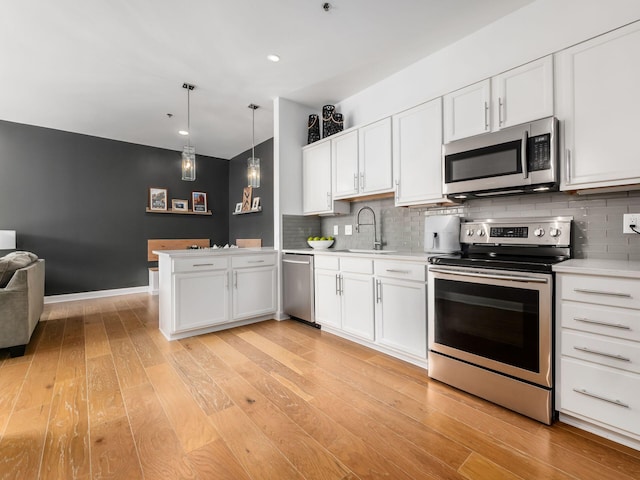 825 N 4th St Unit 215, Columbus, OH 43215 - kitchen with appliances with stainless steel finishes, light countertops, open floor plan, white cabinetry, and tasteful backsplash