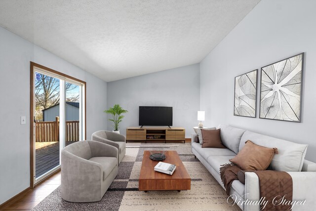 5722 Silver Spurs Ln, Galloway, OH 43119 - living room with lofted ceiling, a textured ceiling, and light wood-type flooring