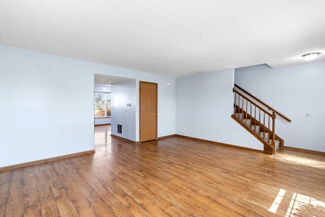 5722 Silver Spurs Ln, Galloway, OH 43119 - unfurnished living room with stairway, wood finished floors, and a textured ceiling