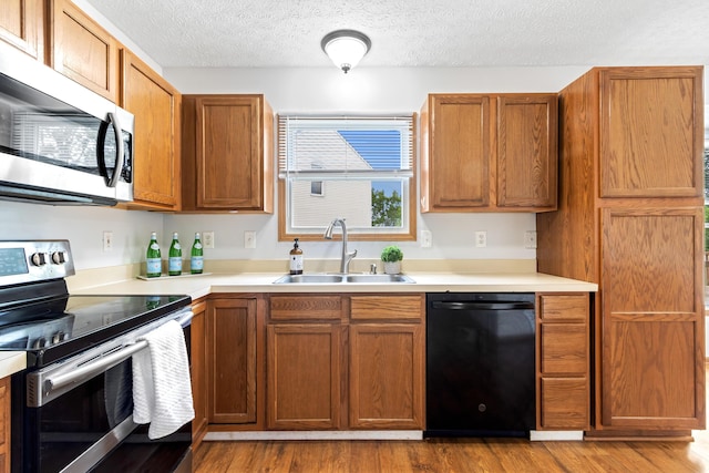 5722 Silver Spurs Ln, Galloway, OH 43119 - kitchen with stainless steel appliances, wood finished floors, light countertops, and a textured ceiling