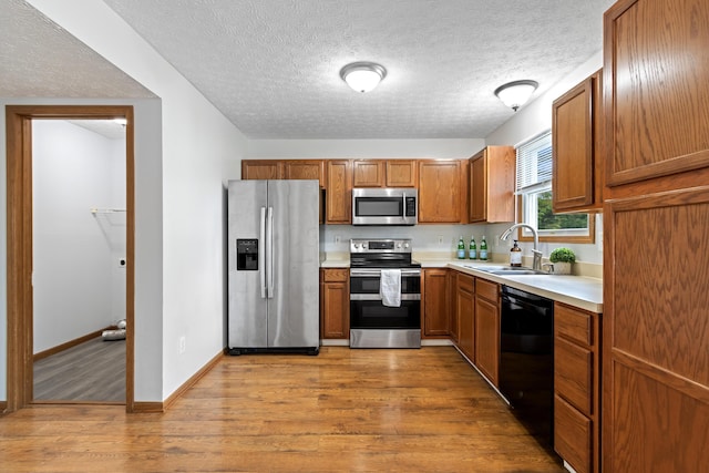 5722 Silver Spurs Ln, Galloway, OH 43119 - kitchen with stainless steel appliances, wood finished floors, brown cabinetry, light countertops, and a textured ceiling