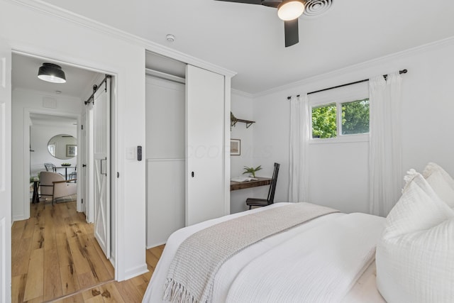 2554 Nottingham Rd, Upper Arlington, OH 43221 - bedroom with a barn door, light wood finished floors, a closet, crown molding, and a ceiling fan
