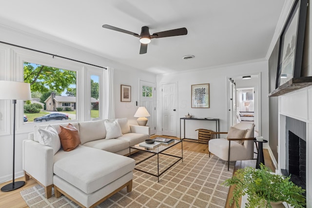 2554 Nottingham Rd, Upper Arlington, OH 43221 - living room with plenty of natural light, a ceiling fan, light wood-type flooring, a brick fireplace, and crown molding