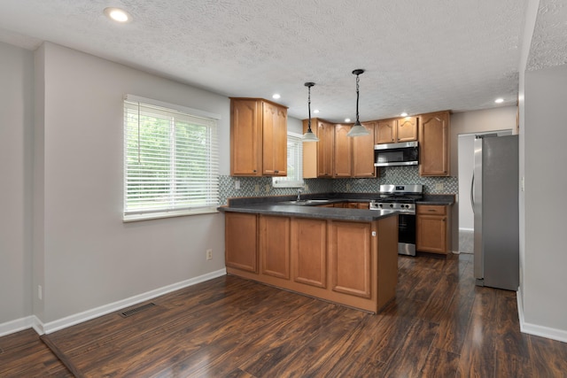 2268 Worthingwoods Blvd, Powell, OH 43065 - kitchen with appliances with stainless steel finishes, a peninsula, dark countertops, dark wood-style floors, and a textured ceiling