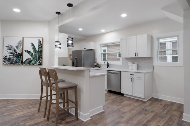 1591 Franklin Ave, Columbus, OH 43205 - kitchen with stainless steel appliances, a breakfast bar, dark wood-type flooring, white cabinets, and recessed lighting