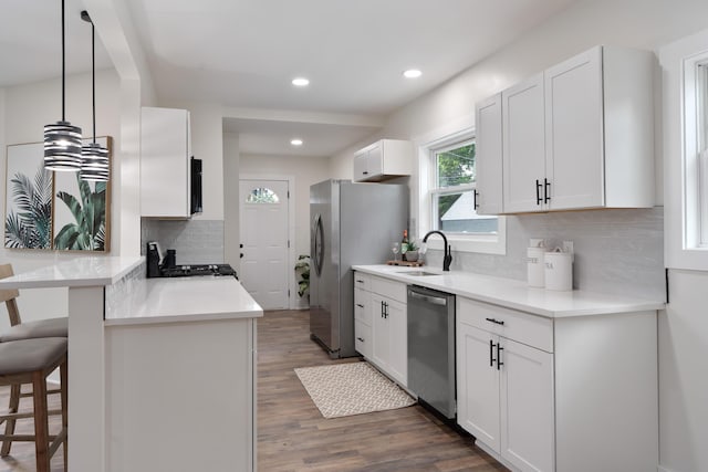 1591 Franklin Ave, Columbus, OH 43205 - kitchen with appliances with stainless steel finishes, a breakfast bar area, a peninsula, tasteful backsplash, and wood finished floors