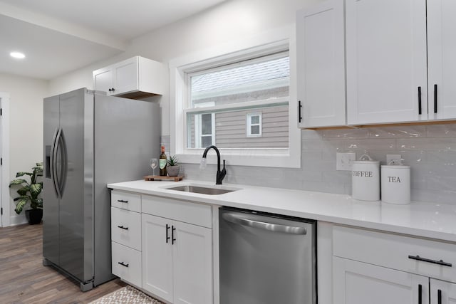 1591 Franklin Ave, Columbus, OH 43205 - kitchen with stainless steel appliances, wood finished floors, decorative backsplash, white cabinetry, and light countertops