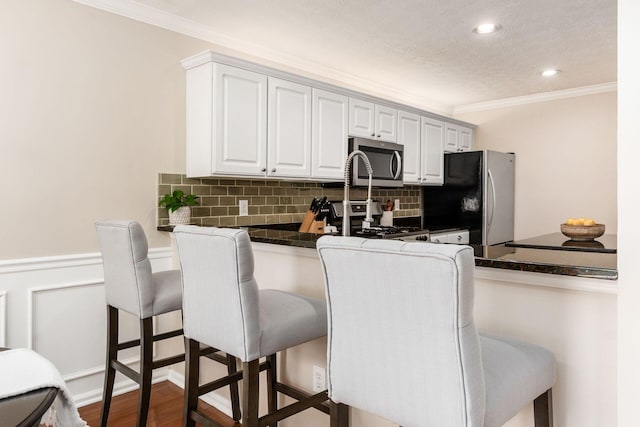 3381 Fishinger Mill Dr, Hilliard, OH 43026 - kitchen featuring appliances with stainless steel finishes, dark countertops, a breakfast bar, tasteful backsplash, and crown molding
