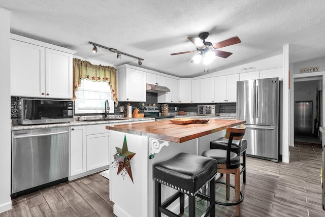 562 Bowman Ln, Chillicothe, OH 45601 - kitchen with stainless steel appliances, wooden counters, under cabinet range hood, a breakfast bar, and white cabinets