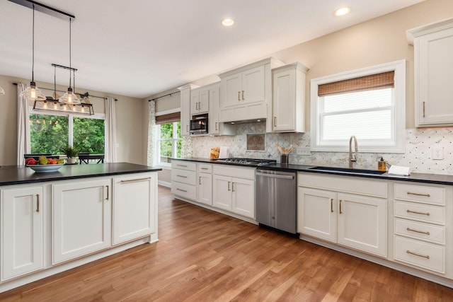 2467 Roe Dr, Lewis Center, OH 43035 - kitchen with stainless steel appliances, dark countertops, light wood-type flooring, backsplash, and decorative light fixtures