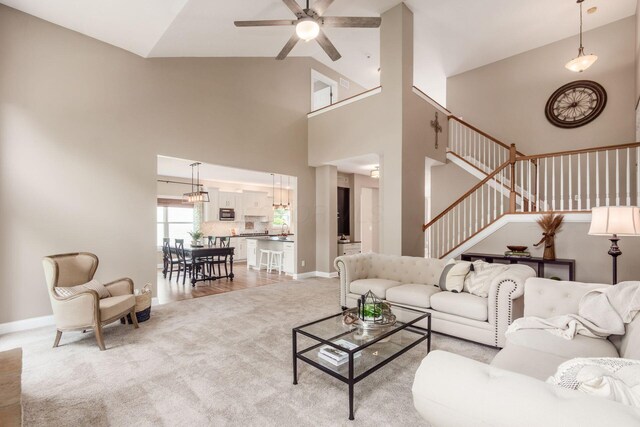2467 Roe Dr, Lewis Center, OH 43035 - living area featuring light carpet, ceiling fan, stairway, and high vaulted ceiling