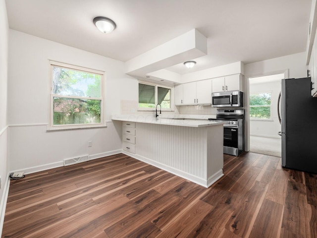 6509 Evening St, Worthington, OH 43085 - kitchen with appliances with stainless steel finishes, a peninsula, dark wood finished floors, light countertops, and white cabinets