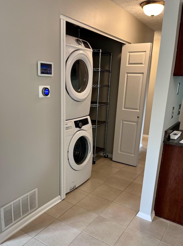 347 W 5th Ave, Columbus, OH 43201 - washroom featuring stacked washing machine and dryer, light tile patterned floors, and a textured ceiling
