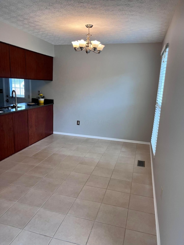 347 W 5th Ave, Columbus, OH 43201 - kitchen with a chandelier, dark countertops, a textured ceiling, light tile patterned floors, and decorative light fixtures