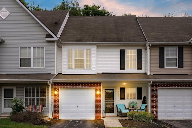 8438 Diversey Loop Unit 504, Blacklick, OH 43004 - townhome / multi-family property featuring covered porch, an attached garage, brick siding, and a shingled roof