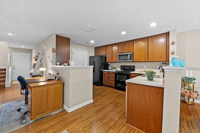 8438 Diversey Loop Unit 504, Blacklick, OH 43004 - kitchen with black appliances, light countertops, light wood-style flooring, a peninsula, and brown cabinetry
