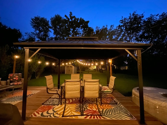 4860 Downing Dr, Columbus, OH 43232 - patio at night with a gazebo, a storage unit, outdoor dining space, and a patio area