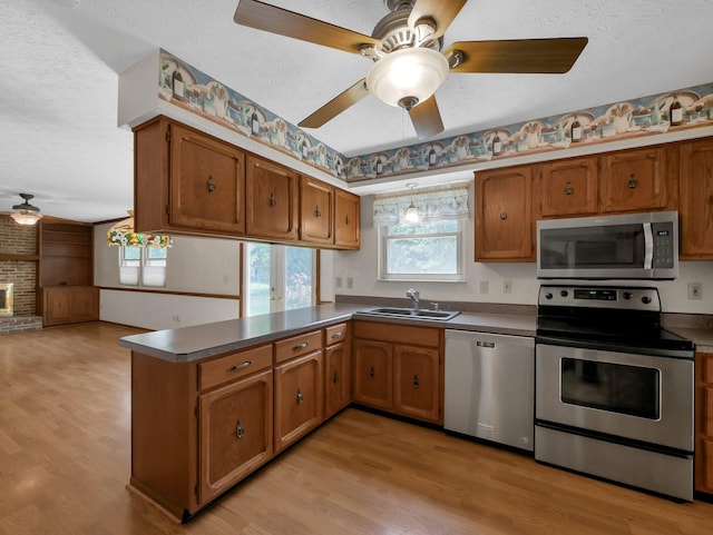 1380 Hanbury Ct, Gahanna, OH 43230 - kitchen featuring appliances with stainless steel finishes, a textured ceiling, a peninsula, light wood-style flooring, and brown cabinetry