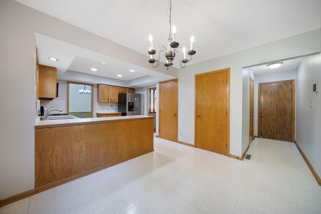 6978 Ernest Way, Dublin, OH 43017 - kitchen with stainless steel fridge, a chandelier, brown cabinetry, light flooring, and pendant lighting