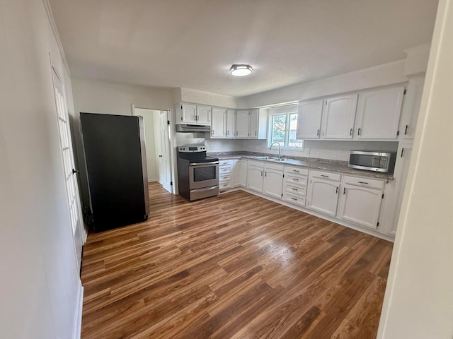 85 Blymer St, Delaware, OH 43015 - kitchen featuring appliances with stainless steel finishes, under cabinet range hood, dark wood finished floors, white cabinetry, and light countertops