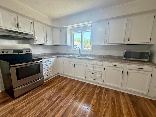 85 Blymer St, Delaware, OH 43015 - kitchen with appliances with stainless steel finishes, under cabinet range hood, white cabinetry, dark wood-style floors, and ornamental molding