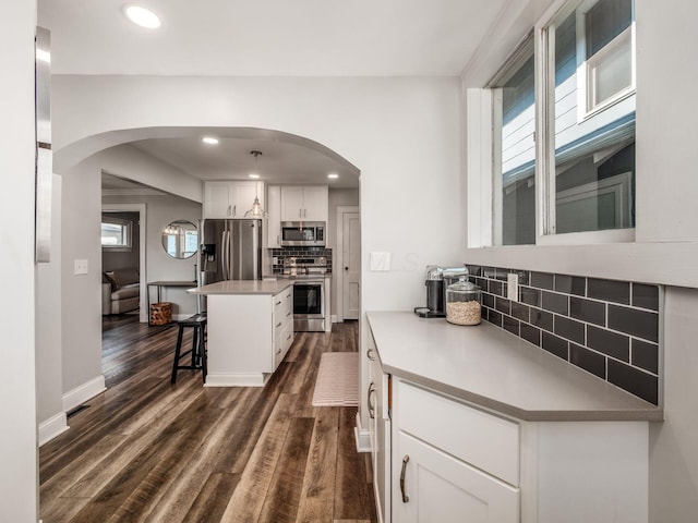 185 Frebis Ave, Columbus, OH 43206 - kitchen featuring stainless steel appliances, arched walkways, dark wood-style flooring, a kitchen bar, and recessed lighting