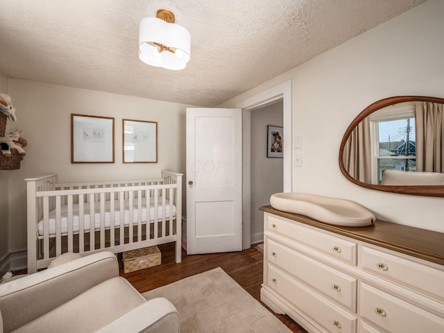185 Frebis Ave, Columbus, OH 43206 - bedroom with dark wood finished floors, a textured ceiling, and a crib