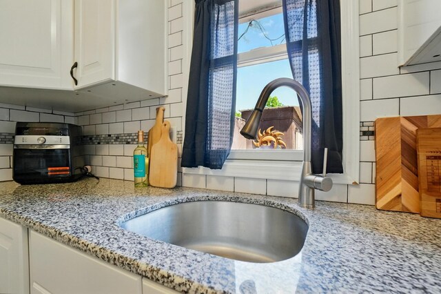 602 Dlyn St Unit H8, Columbus, OH 43228 - kitchen view of decorative backsplash, white cabinetry, and light stone countertops
