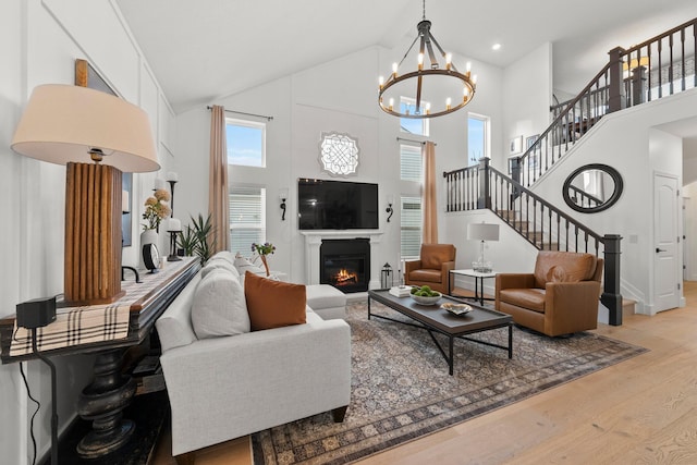 5431 Goose Falls Dr, Dublin, OH 43016 - living area with light wood-type flooring, high vaulted ceiling, a chandelier, a glass covered fireplace, and stairway