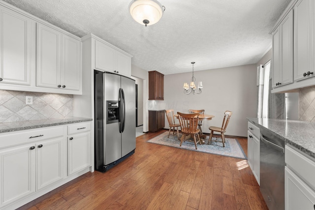 12475 Oak Dr, Orient, OH 43146 - kitchen featuring appliances with stainless steel finishes, light wood-type flooring, backsplash, a chandelier, and a textured ceiling