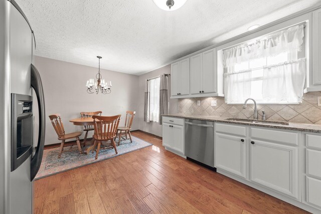 12475 Oak Dr, Orient, OH 43146 - kitchen with appliances with stainless steel finishes, decorative backsplash, a textured ceiling, light wood-style flooring, and a chandelier