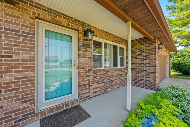 12475 Oak Dr, Orient, OH 43146 - doorway to property with covered porch, an attached garage, brick siding, and concrete driveway