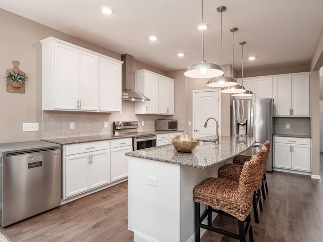 404 Colony Ridge Dr, Delaware, OH 43015 - kitchen featuring appliances with stainless steel finishes, wall chimney range hood, dark wood-style floors, decorative backsplash, and a breakfast bar area