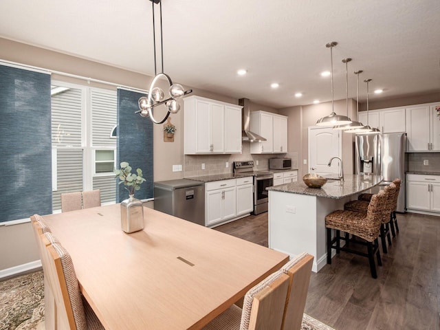 404 Colony Ridge Dr, Delaware, OH 43015 - kitchen featuring appliances with stainless steel finishes, wall chimney range hood, a chandelier, decorative backsplash, and dark wood-type flooring